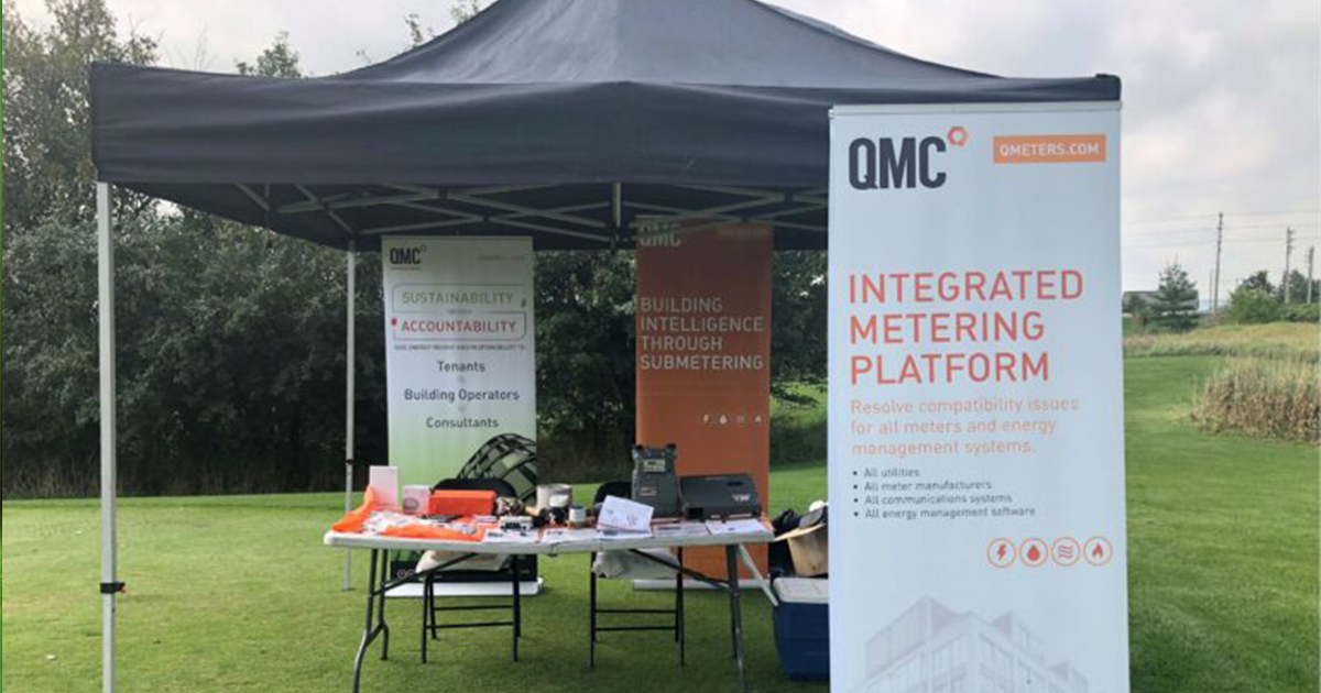 A QMC branded tent at a golf tournament showcasing the companies metering solutions.